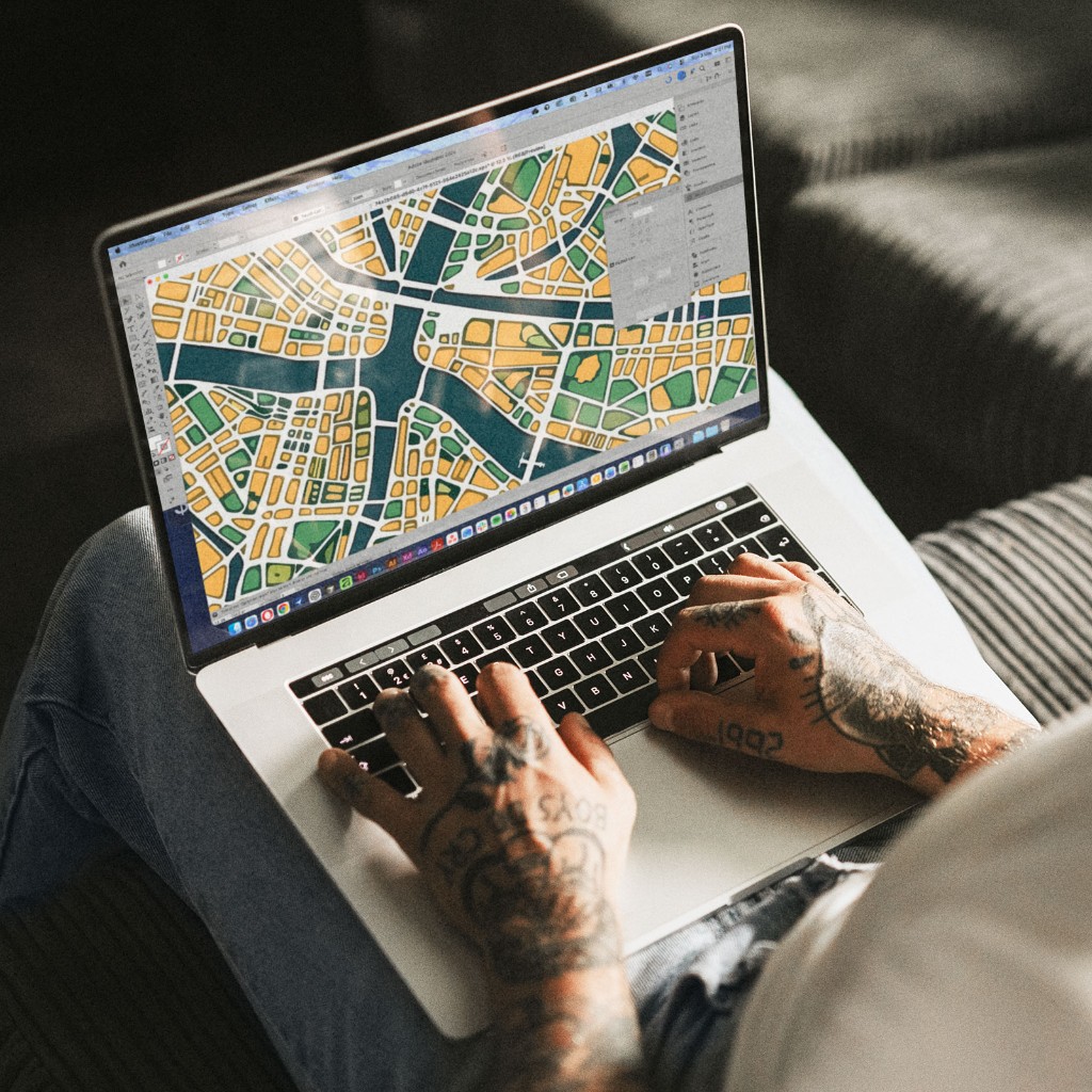 Designer editing a colourful vector map on a laptop